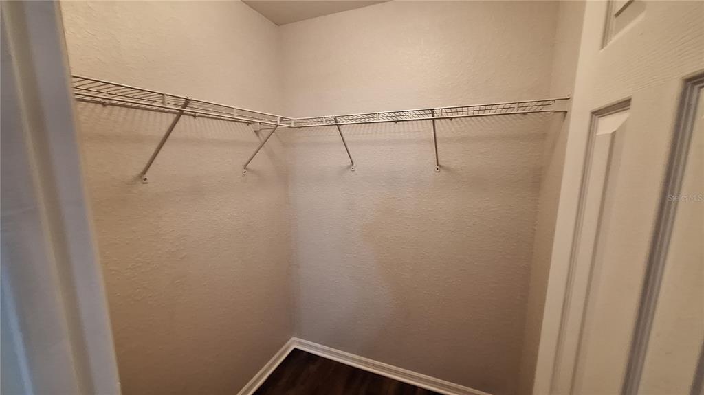 A small walk-in closet features white wire shelving and dark wood-look flooring — 80 PECAN PASS, OCALA, FL