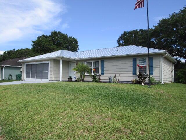 A single-story house with light siding, a metal roof, and a screened-in garage — 732 Bayfront Terrace, Sebastian FL 32958, SEBASTIAN, FL