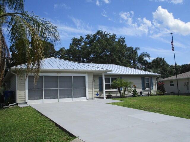 A single-story house with a metal roof, a screened garage, and a concrete driveway — 732 Bayfront Terrace, Sebastian FL 32958, SEBASTIAN, FL