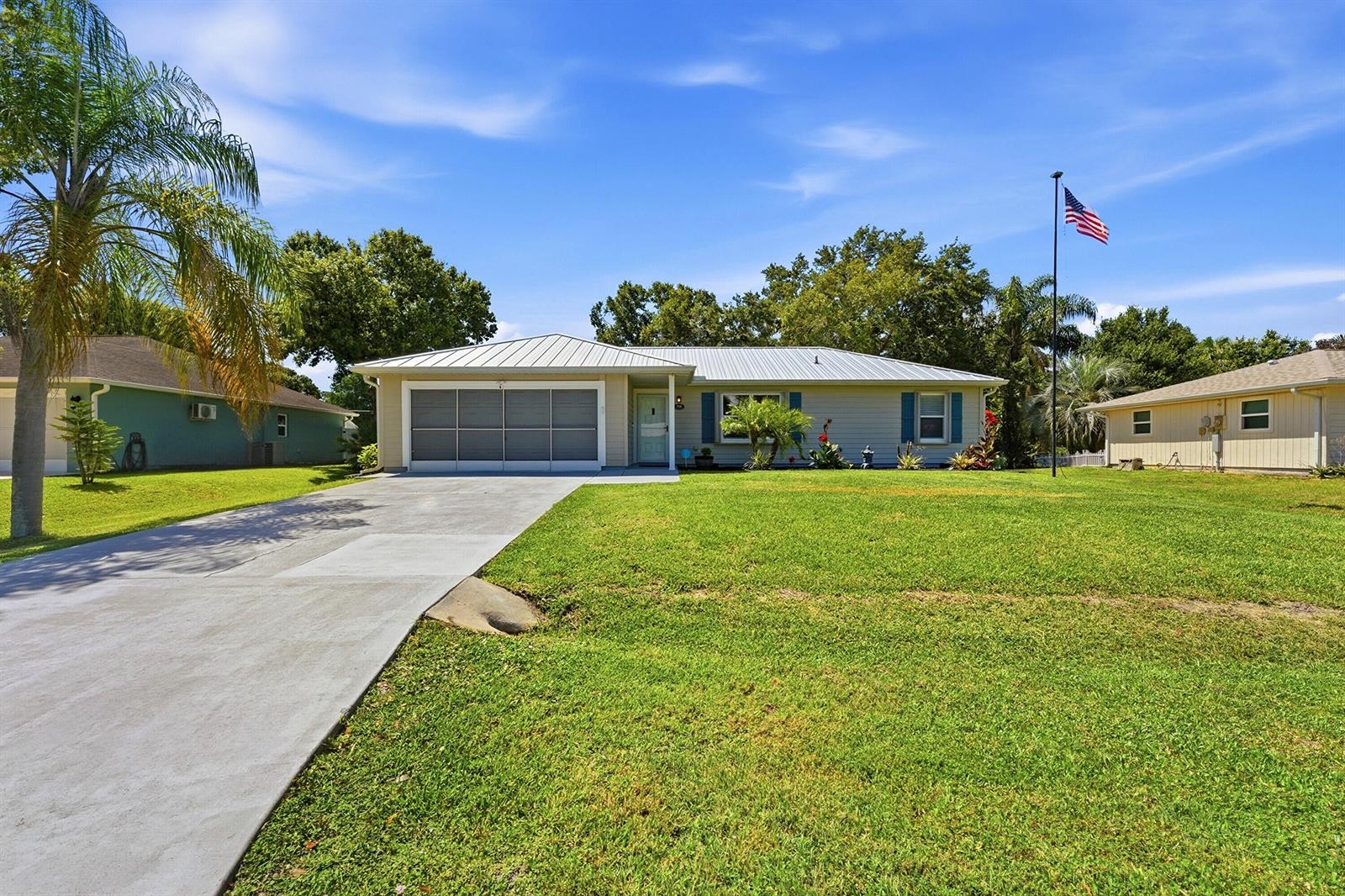 A single-story house with a metal roof, garage, and American flag on a lawn — 732 Bayfront Terrace, Sebastian FL 32958, SEBASTIAN, FL