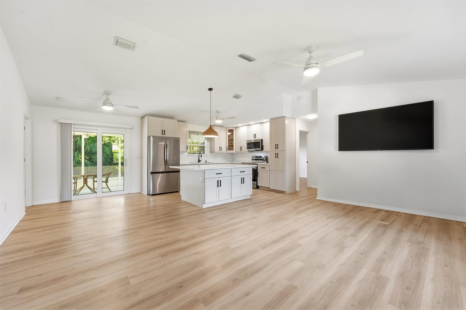 An open-concept kitchen with white cabinetry, a center island, and light wood-look flooring — 732 Bayfront Terrace, Sebastian FL 32958, SEBASTIAN, FL