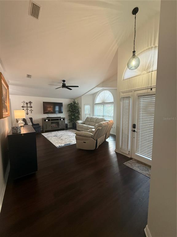 A living room with dark wood floors, a large area rug, and white leather furniture — 6060 CONDOR DRIVE, LAKELAND, FL