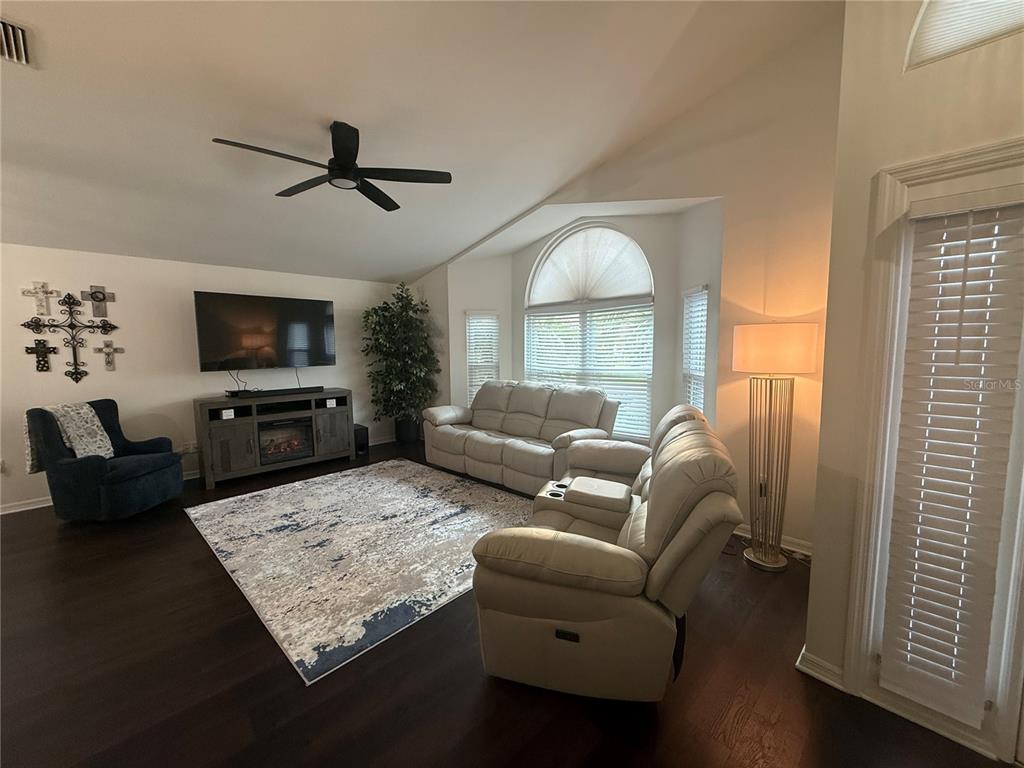 A living room features dark wood floors, a vaulted ceiling, and a glass-paneled front door — 6060 CONDOR DRIVE, LAKELAND, FL