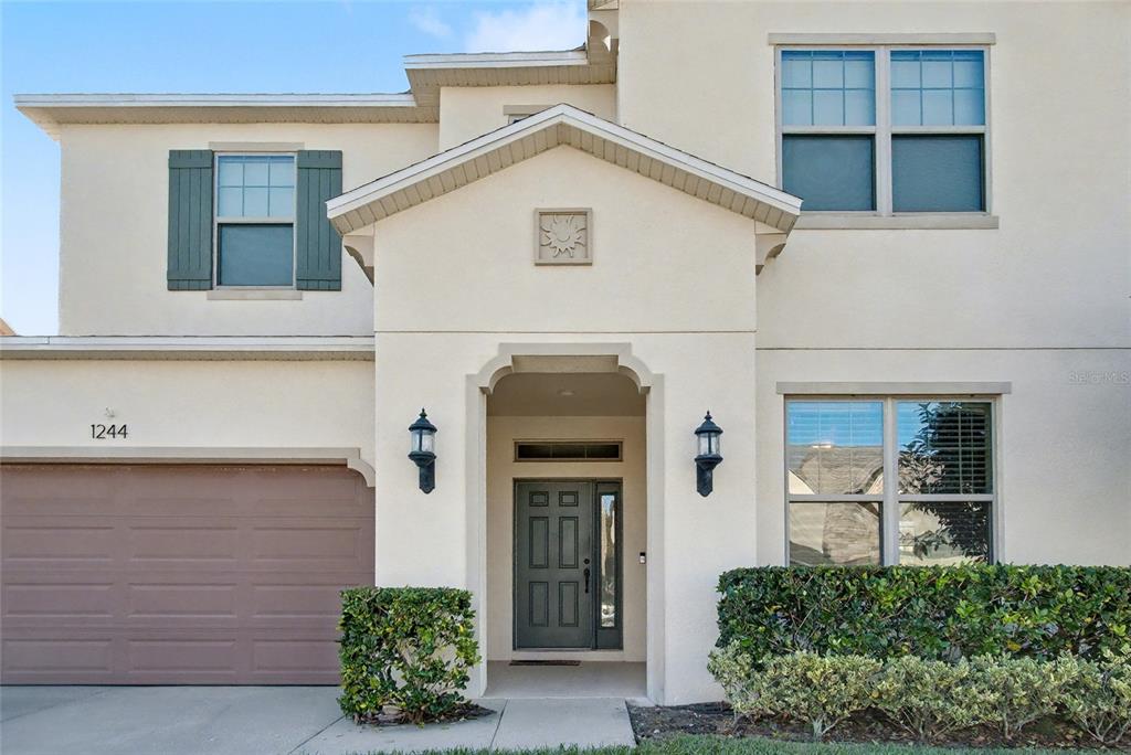 A two-story house exterior features a beige stucco facade, a garage, and a front entryway — 1244 GATEWOOD AVENUE, MINNEOLA, FL