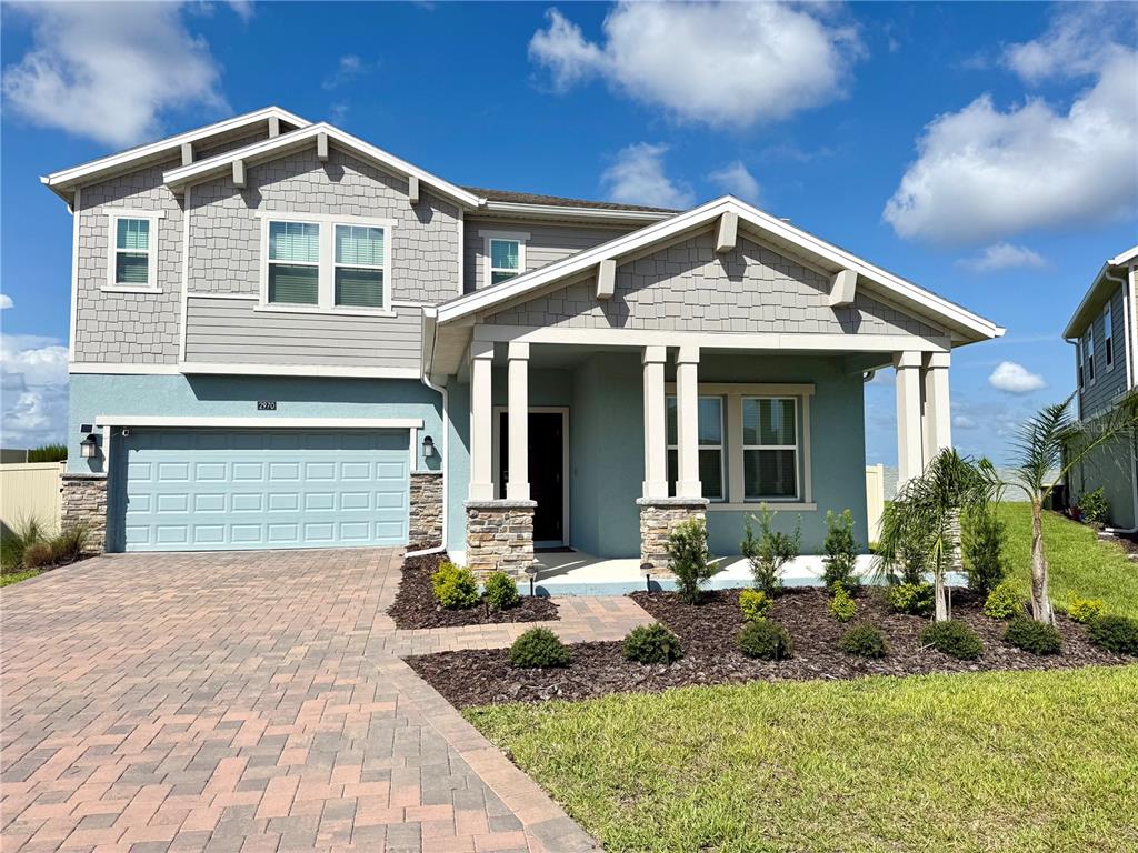 A two-story house with a paved driveway, stone accents, and a covered front porch — 2970 ARMSTRONG AVENUE, CLERMONT, FL