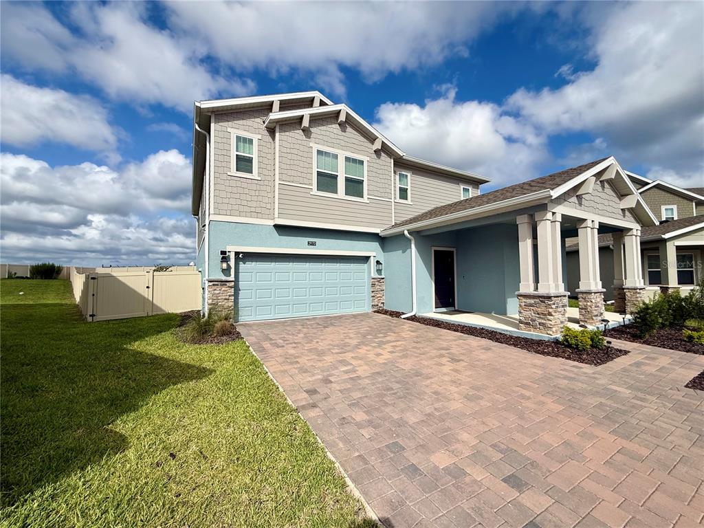 A two-story house with a blue stucco exterior, stone accents, and a paved driveway — 2970 ARMSTRONG AVENUE, CLERMONT, FL
