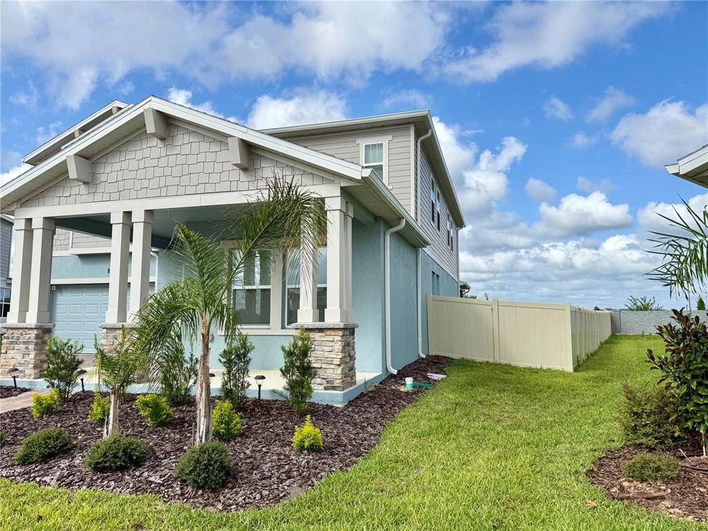 A light blue house with stone-based columns and a vinyl fence in the side yard — 2970 ARMSTRONG AVENUE, CLERMONT, FL