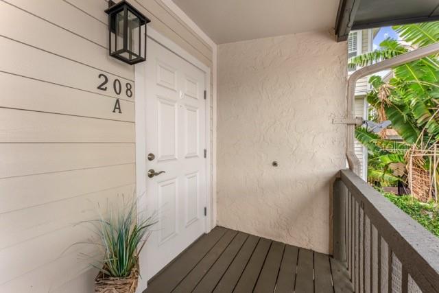 An exterior view of a residential apartment entrance with a white door and balcony — 527 S LINCOLN AVENUE UNIT A208, TAMPA, FL