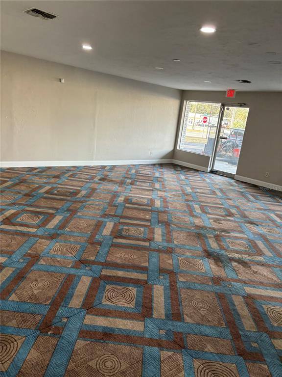 An empty commercial space features patterned carpet flooring, recessed ceiling lights, and a glass entrance door — 1780 E DUVAL STREET UNIT 3, LAKE CITY, FL