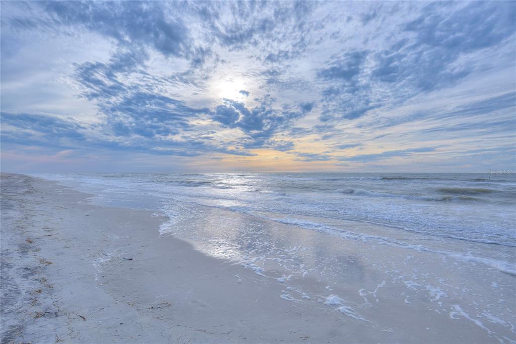 An aerial view of a multi-story beachfront condominium building with a pool and parking lot — 1660 GULF BOULEVARD UNIT PH1, CLEARWATER BEACH, FL