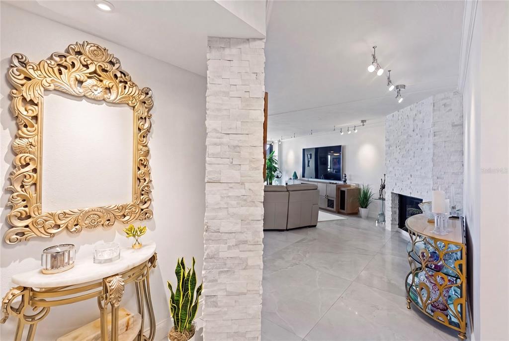 A bright entryway features white walls, marble-style tile flooring, a gold console table, and track lighting — 1660 GULF BOULEVARD UNIT PH1, CLEARWATER BEACH, FL