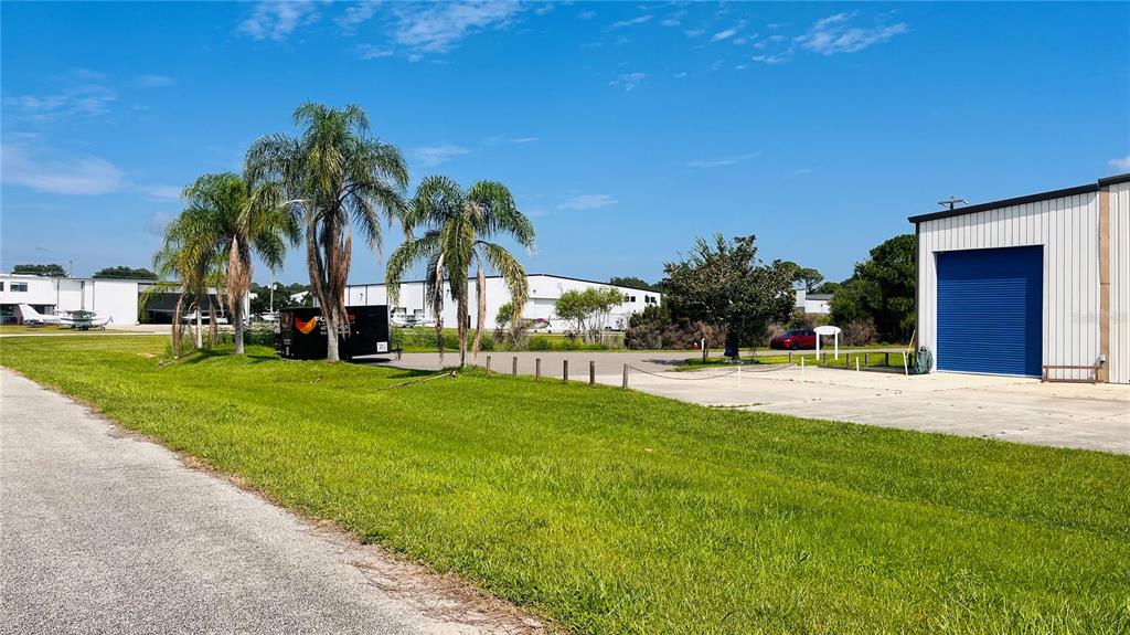 An exterior view of a hangar building with a blue roll-up door and palm trees — 541 SKYWAY DRIVE, EDGEWATER, FL