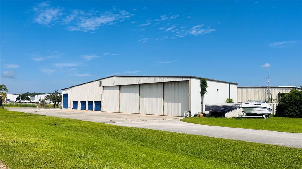A large metal warehouse building with multiple bay doors sits on a grassy lot — 541 SKYWAY DRIVE, EDGEWATER, FL