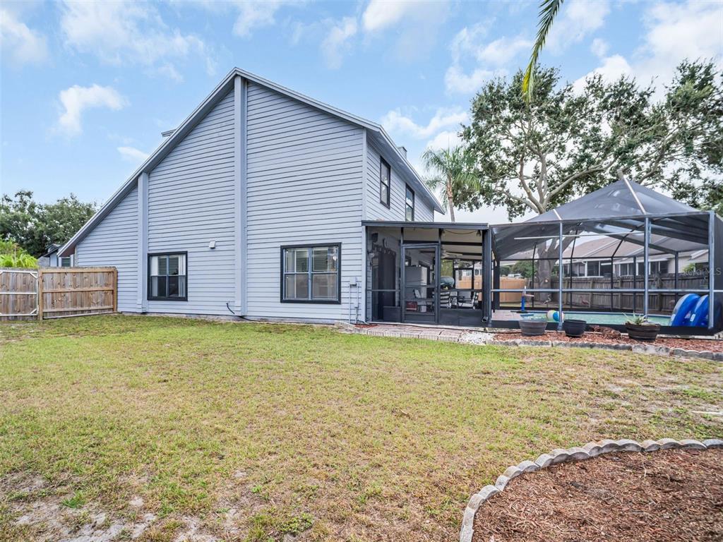 A living room features a vaulted ceiling, a staircase with gray railings, and tile flooring — 3177 MONTROSE PLACE, PALM HARBOR, FL