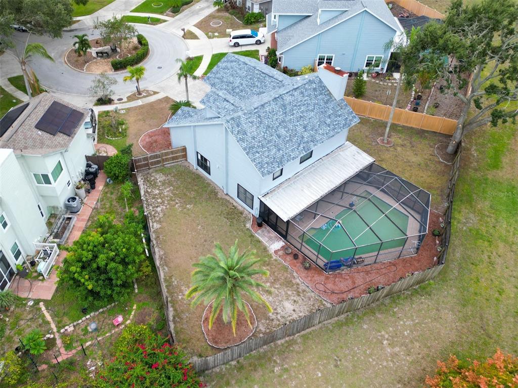 An aerial view shows a suburban house with a gray roof and a screened-in pool — 3177 MONTROSE PLACE, PALM HARBOR, FL