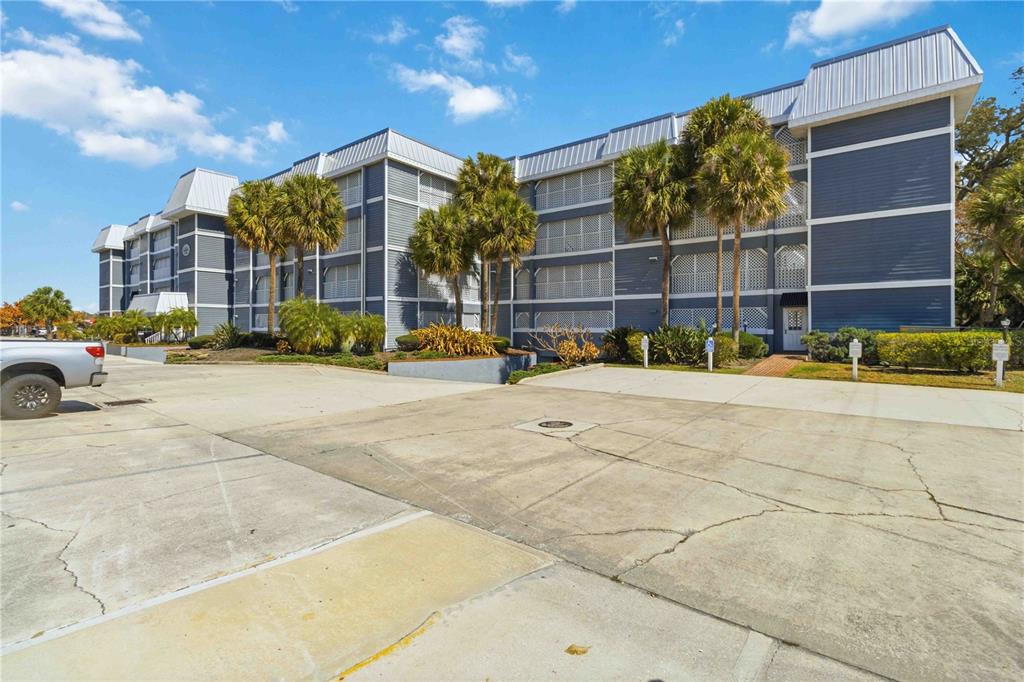 A multi-story blue apartment building stands behind a large, cracked concrete parking lot — 905 N HARBOR CITY BOULEVARD UNIT 204, MELBOURNE, FL
