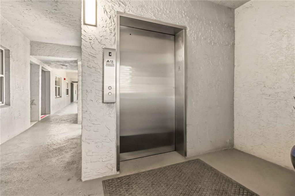 A stainless steel elevator door is set into a textured white wall in a hallway — 905 N HARBOR CITY BOULEVARD UNIT 204, MELBOURNE, FL