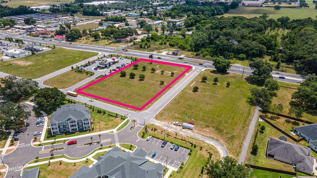 An aerial view shows a vacant rectangular lot outlined in pink near a road intersection — 11532 N US HIGHWAY 301, OXFORD, FL