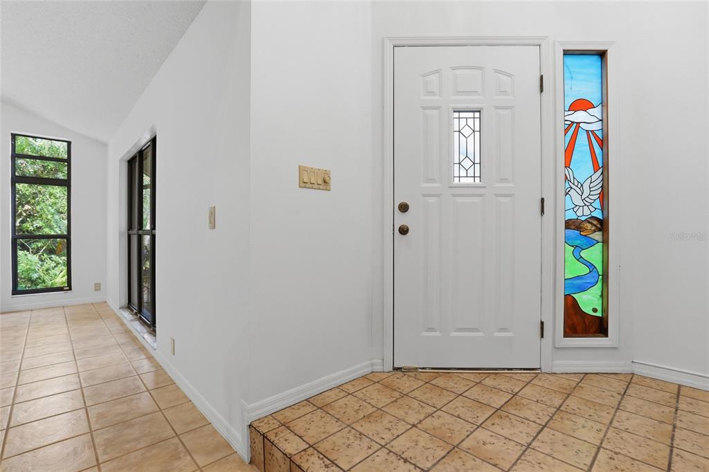 An entryway features a white front door with a stained glass sidelight and tiled floors — 7336 CURLEW STREET, SARASOTA, FL