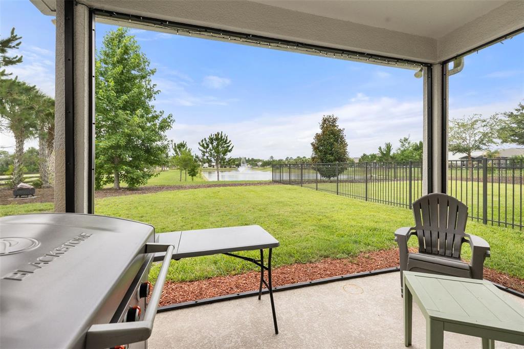A screened-in patio overlooks a grassy backyard with a pond and fountain — 17023 GOLDCREST LOOP, CLERMONT, FL