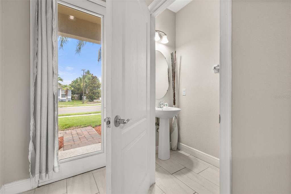 A half bathroom with a pedestal sink and a glass door leading to the outdoors — 17023 GOLDCREST LOOP, CLERMONT, FL