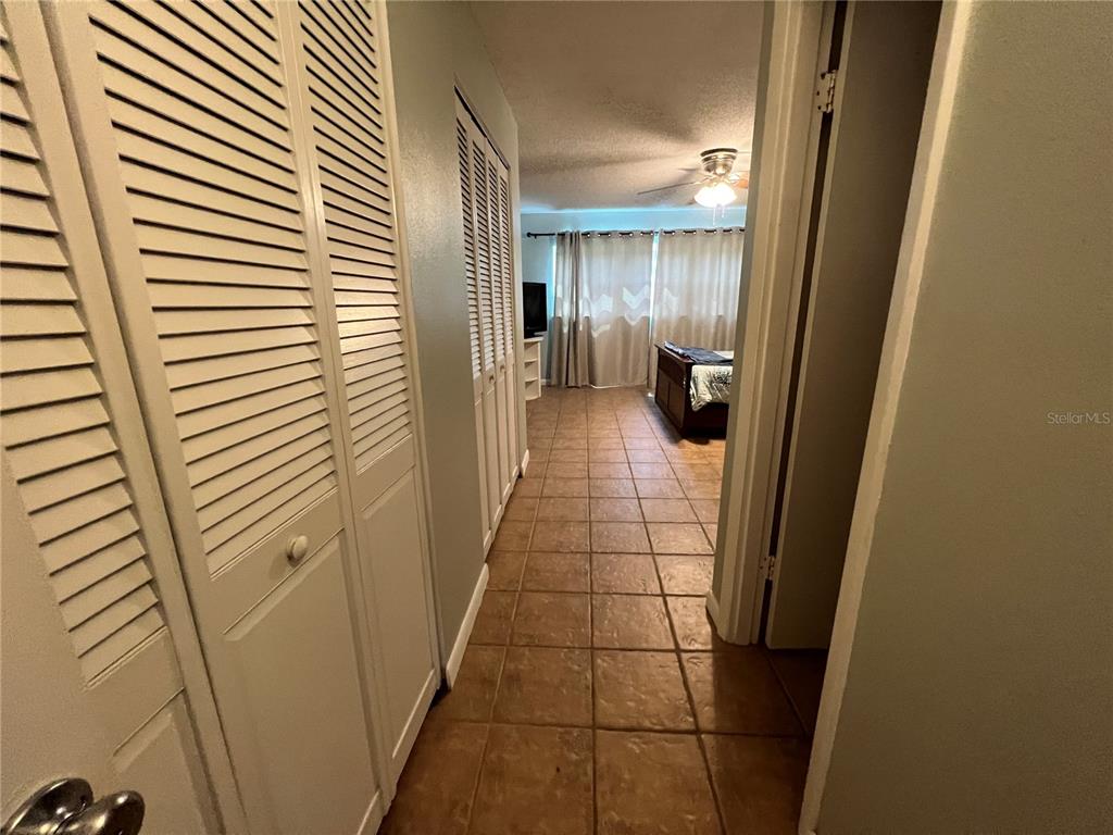A tiled hallway leads past louvered closet doors into a bedroom with a ceiling fan — 2100 OCEAN SHORE BOULEVARD UNIT 1150, ORMOND BEACH, FL