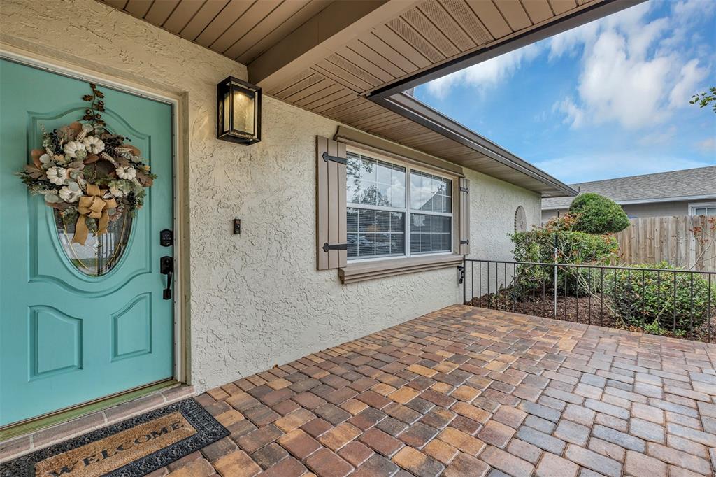 A teal front door with a wreath opens onto a paved porch with a window — 521 AMERICAN HERITAGE PARKWAY, ORLANDO, FL