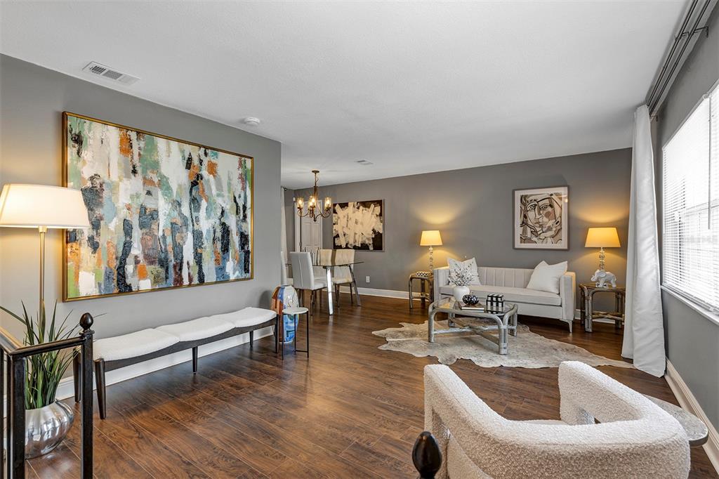 A living room with gray walls, wood-look flooring, abstract art, and a white sofa — 521 AMERICAN HERITAGE PARKWAY, ORLANDO, FL