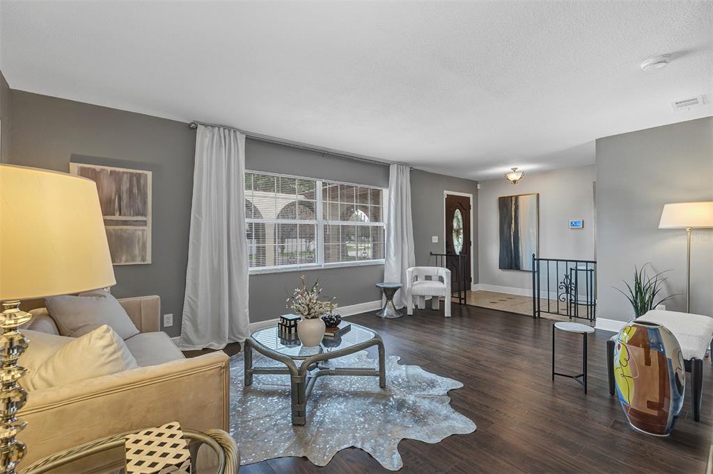 A living room features dark wood floors, gray walls, a cowhide rug, and a front door — 521 AMERICAN HERITAGE PARKWAY, ORLANDO, FL