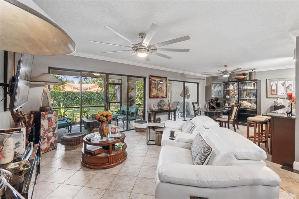 A living room with white leather sofas, tile flooring, and sliding glass doors to a patio — 7913 BAYSIDE VIEW DRIVE, ORLANDO, FL