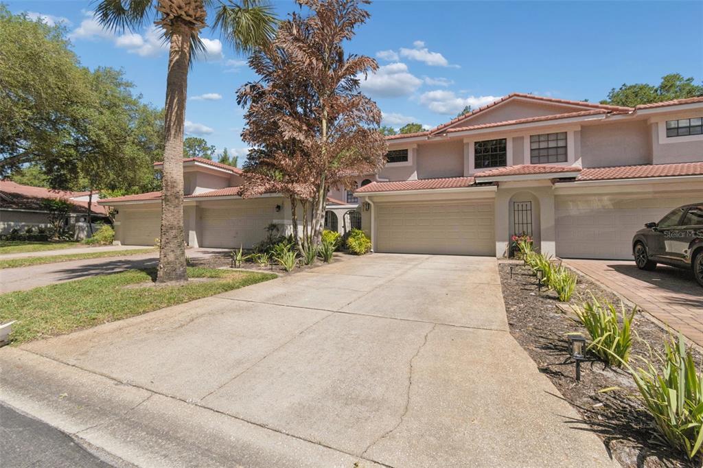 A two-story townhouse exterior with a concrete driveway, two-car garage, and a palm tree — 7913 BAYSIDE VIEW DRIVE, ORLANDO, FL