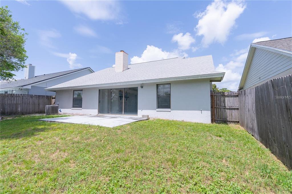 The rear exterior of a single-story house features a concrete patio and a fenced yard — 660 HOLBROOK CIRCLE, LAKE MARY, FL