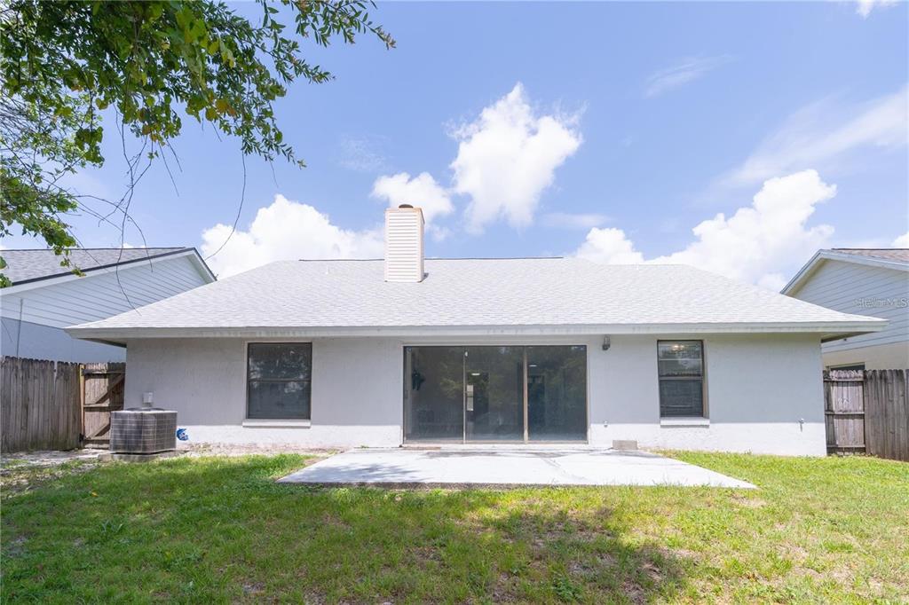 The back exterior of a single-story house features a concrete patio and a chimney — 660 HOLBROOK CIRCLE, LAKE MARY, FL