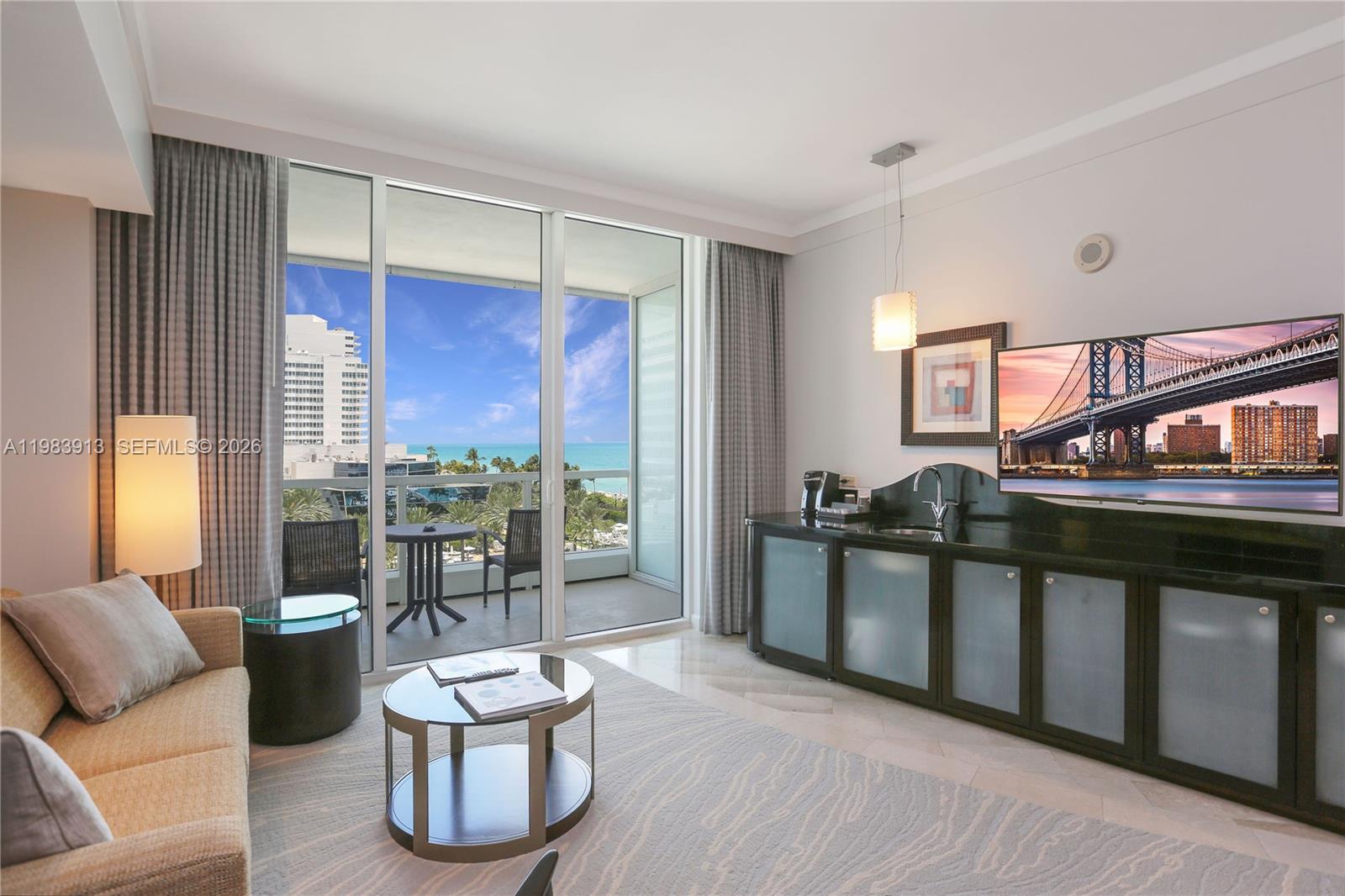 A living room features a sofa, a coffee table, a wet bar, and a balcony view — 4391 Collins Ave # 605, Miami Beach FL 33140, MIAMI BEACH, FL