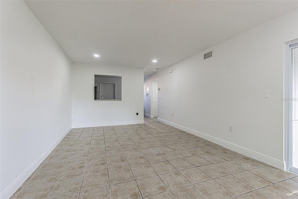 An empty room with white walls, tile flooring, recessed lighting, and a kitchen pass-through window — 556 CLEARWATER LARGO ROAD N UNIT D, LARGO, FL