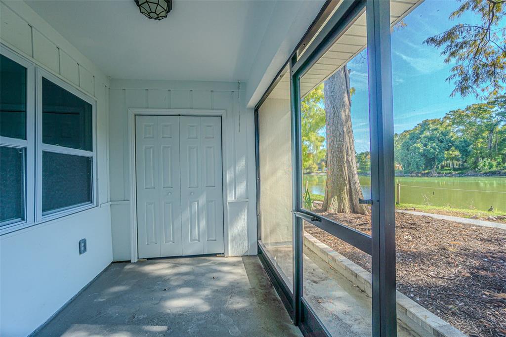 A screened-in porch with a concrete floor, white walls, and a view of a lake — 556 CLEARWATER LARGO ROAD N UNIT D, LARGO, FL