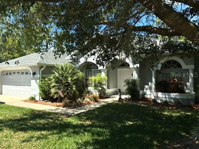 A single-story house with a white garage and arched entryway sits under a large tree — 66 LONE PINE STREET, HOMOSASSA, FL