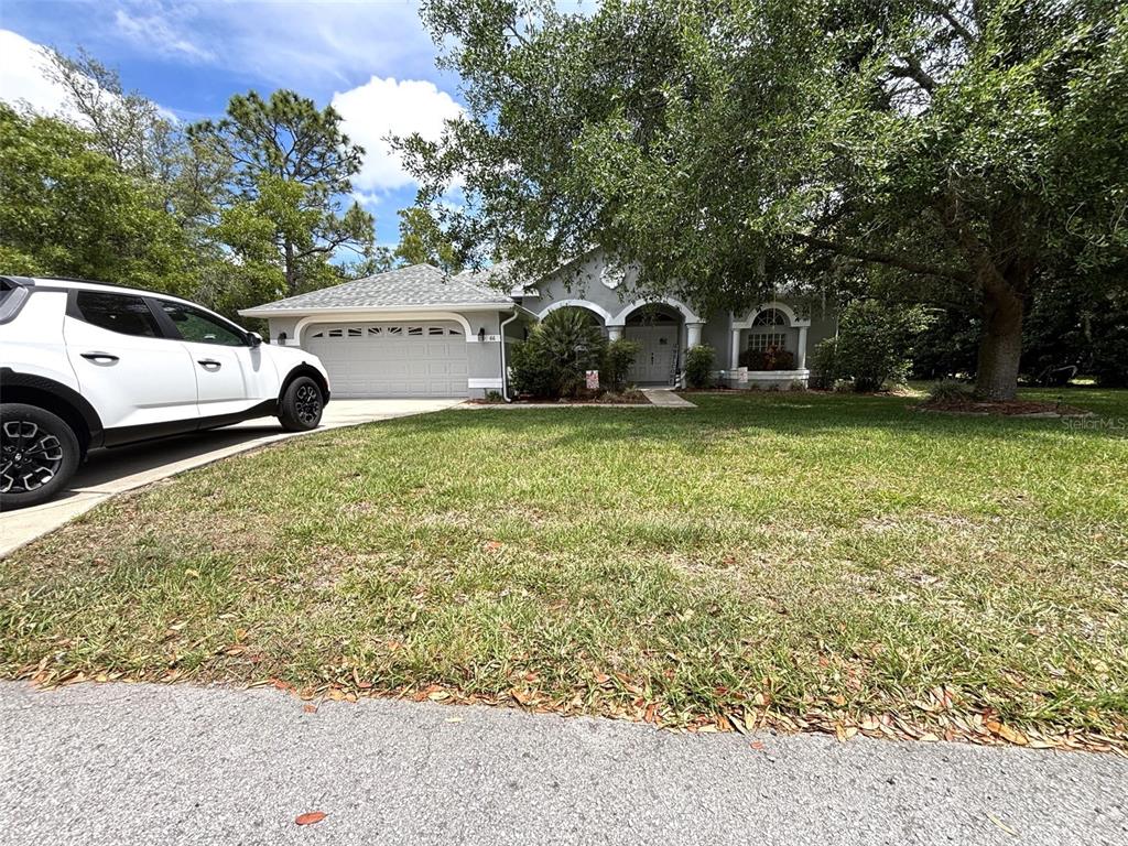 A single-story house with a white garage and a large tree in the front yard — 66 LONE PINE STREET, HOMOSASSA, FL