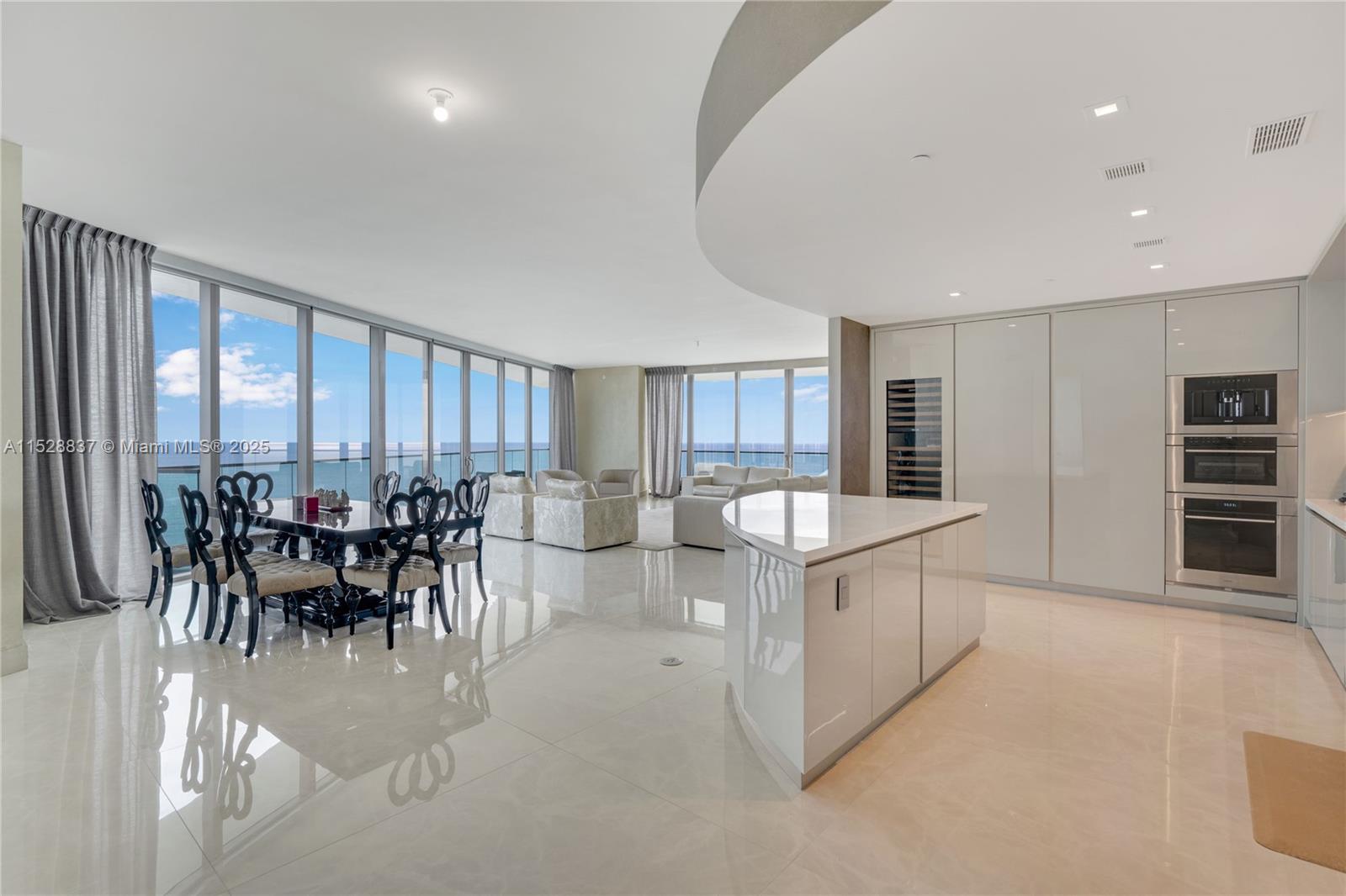 A modern open-concept living and dining area features floor-to-ceiling windows with ocean views — 18975 Collins Ave # 2000, Sunny Isles Beach FL 33160, SUNNY ISLES BEACH, FL