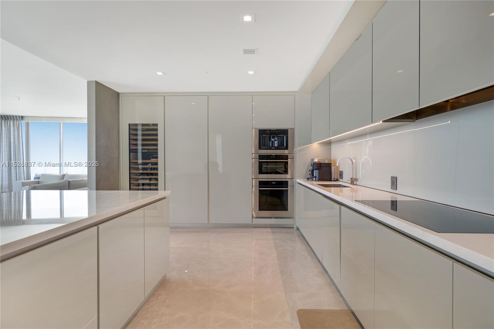 A modern kitchen features glossy light gray cabinetry, stainless steel appliances, and a marble floor — 18975 Collins Ave # 2000, Sunny Isles Beach FL 33160, SUNNY ISLES BEACH, FL