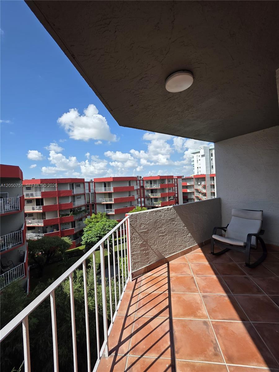 A balcony with terracotta tile flooring, a white metal railing, and a rocking chair — 1750 W 46th St # 520, Hialeah FL 33012, HIALEAH, FL