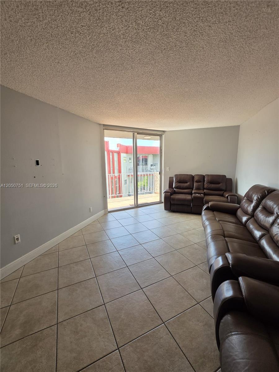 A living room features light gray walls, beige tile flooring, and a sliding glass balcony door — 1750 W 46th St # 520, Hialeah FL 33012, HIALEAH, FL