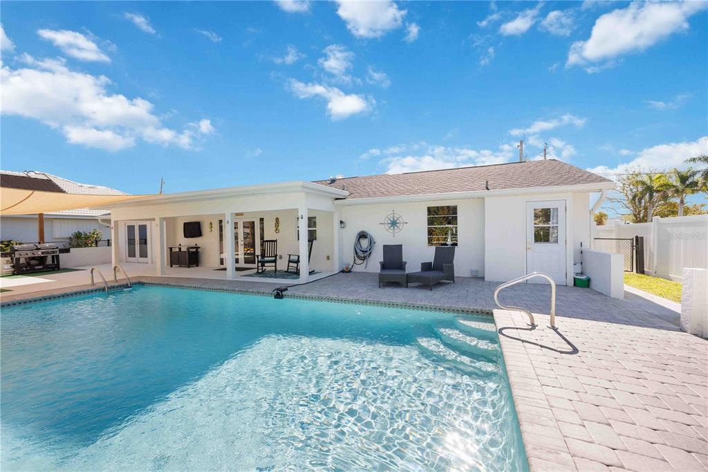 A backyard features a swimming pool with steps, a covered patio, and a paved deck — 5281 BOYLE TERRACE, PORT CHARLOTTE, FL