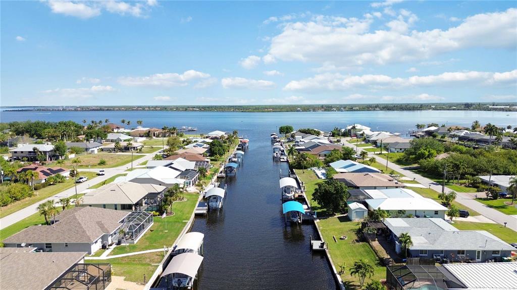 An aerial view shows a canal lined with residential houses and private boat docks — 5281 BOYLE TERRACE, PORT CHARLOTTE, FL