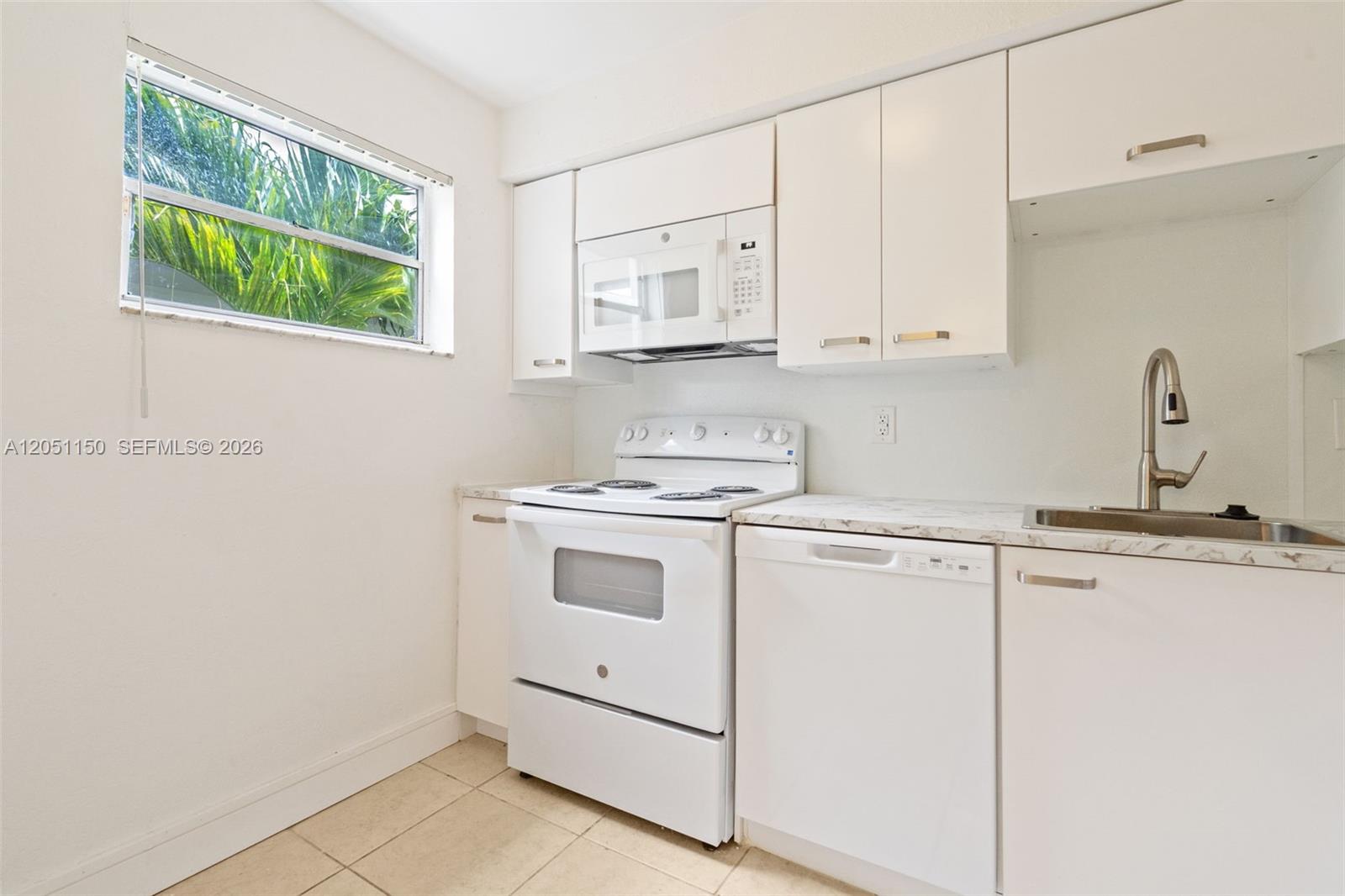 A kitchen features white cabinets, white appliances, a marble-patterned countertop, and a window — 4215 N University Dr # 305, Sunrise FL 33351, SUNRISE, FL