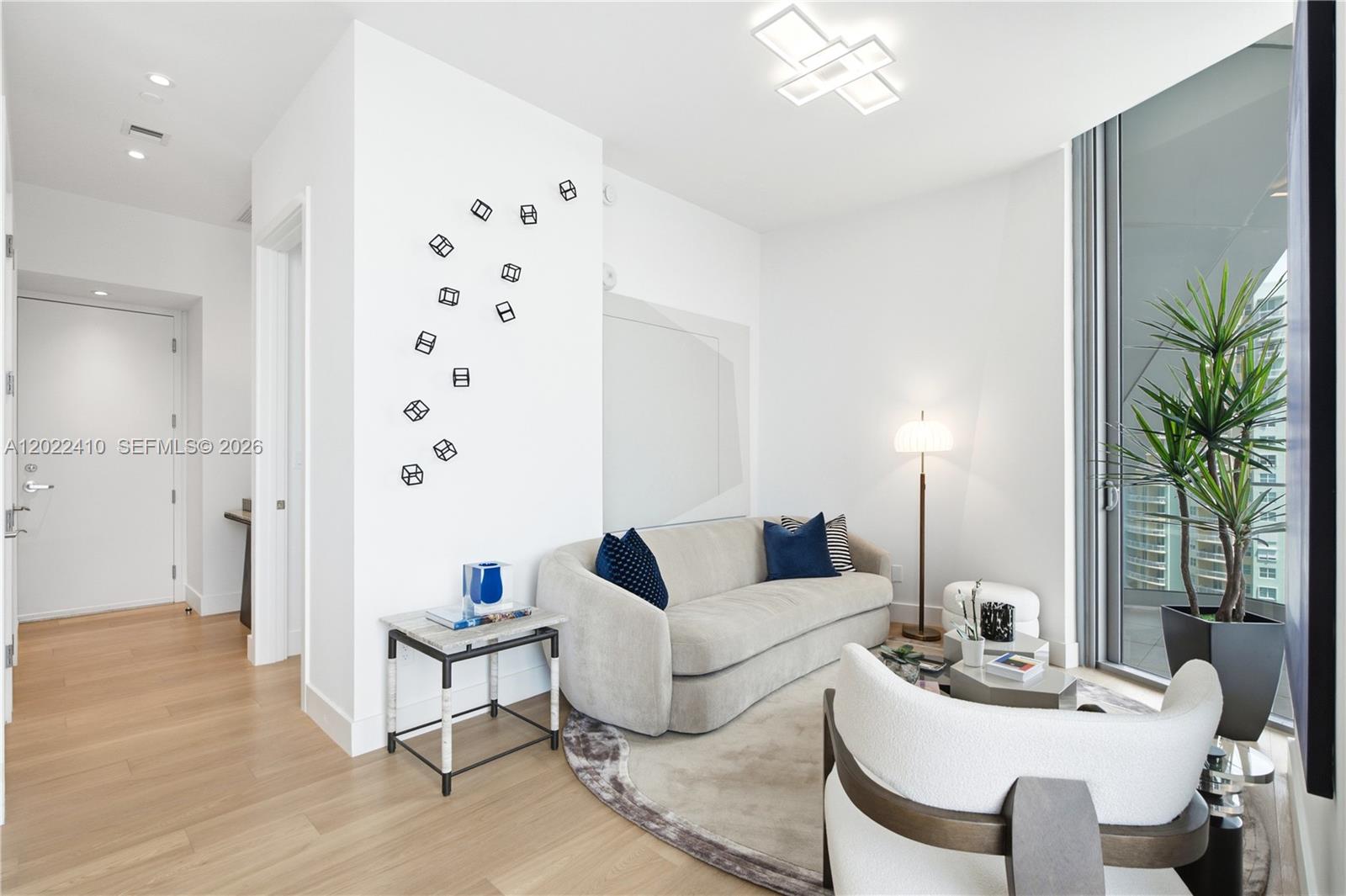 A modern living room features a beige sofa, a round rug, and geometric wall art — 175 SE 25th Rd # 1604, Miami FL 33129, MIAMI, FL