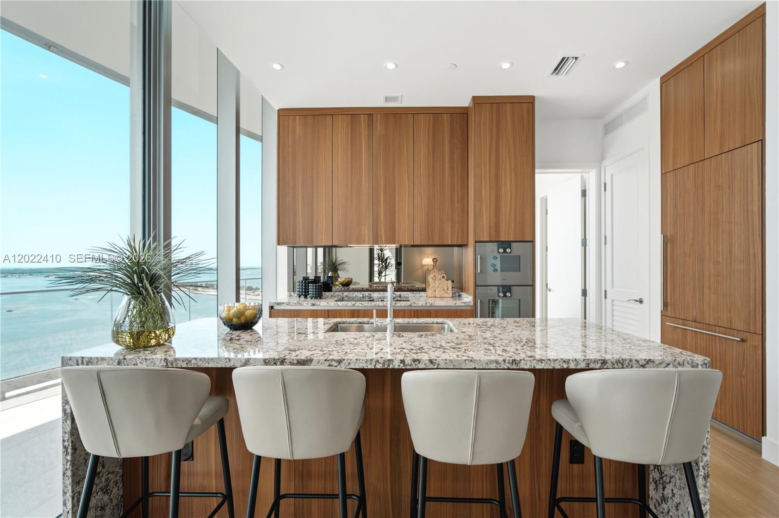A modern kitchen features wood cabinetry, granite countertops, a central island, and floor-to-ceiling windows — 175 SE 25th Rd # 1604, Miami FL 33129, MIAMI, FL