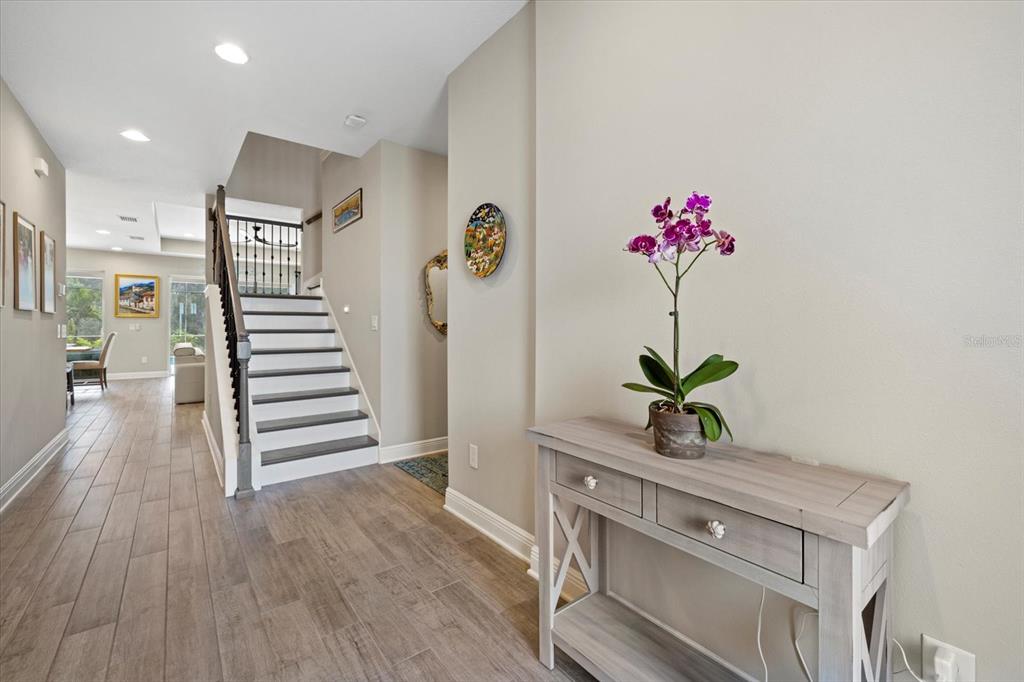 A foyer features wood-look tile flooring, a staircase with dark railings, and a console table — 16750 SAVORY MIST CIRCLE, BRADENTON, FL
