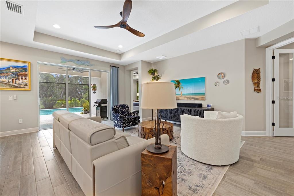 A living room features a white sofa, a round chair, and a view of a pool — 16750 SAVORY MIST CIRCLE, BRADENTON, FL