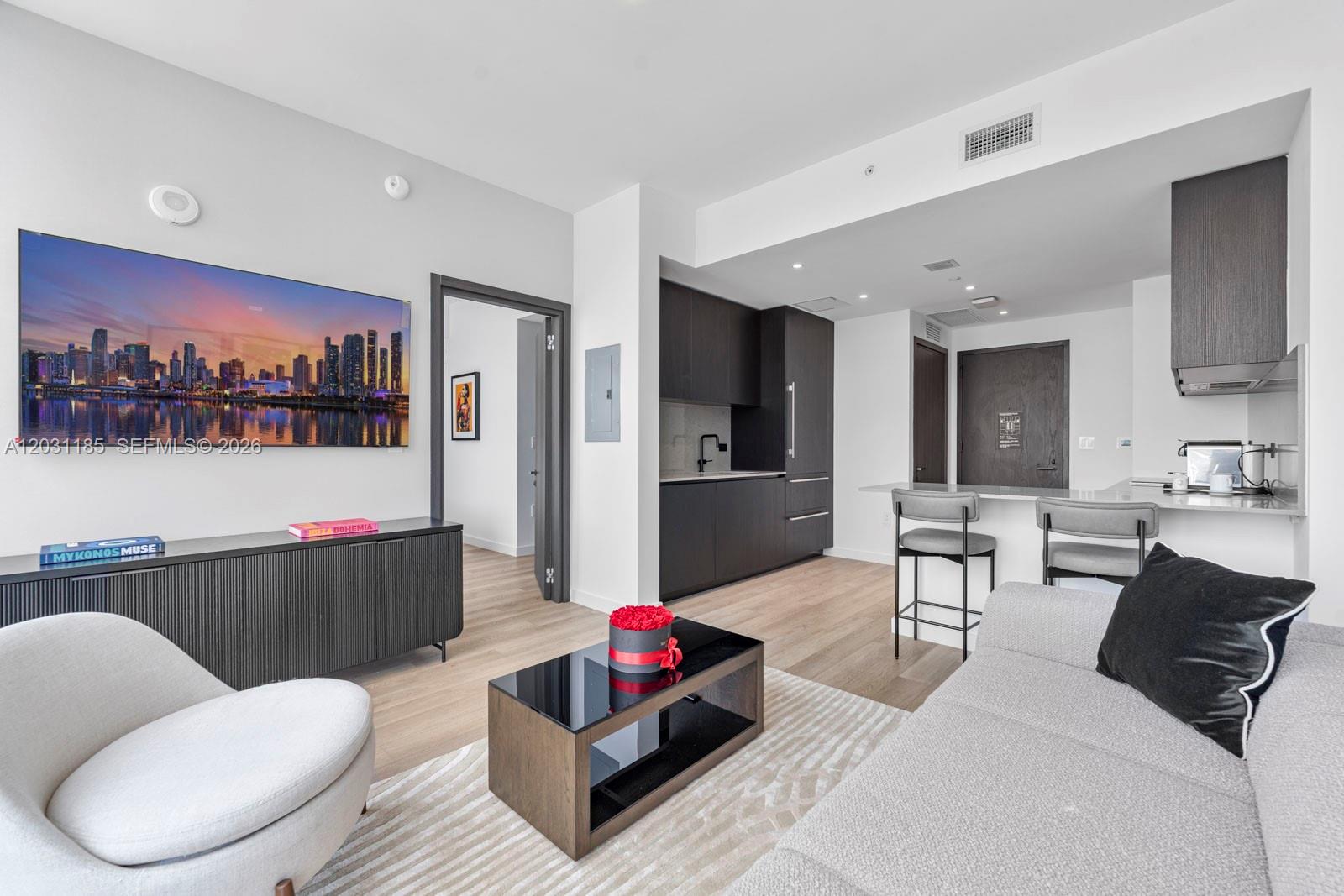 A modern living room features a television, dark cabinetry, and a kitchen island with stools — 20 NE 11th Street # 4309, Miami FL 33132, MIAMI, FL
